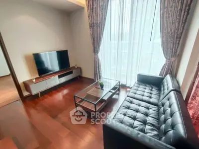 Modern living room with sleek leather sofa and large TV, featuring elegant curtains and wooden flooring.