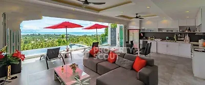 Luxurious open-plan living room with stunning pool and ocean view, modern kitchen, and stylish decor.