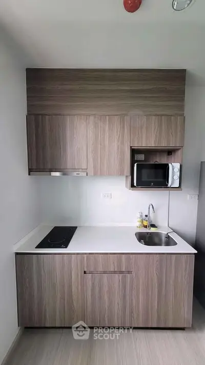 Modern compact kitchen with sleek cabinetry and built-in microwave