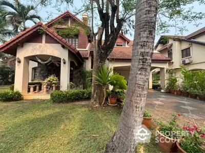 Charming two-story home with terracotta roof tiles, nestled in lush greenery with a well-manicured lawn and inviting entrance, exuding a warm, family-friendly atmosphere.