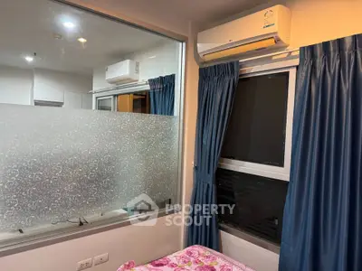 Cozy bedroom with air conditioning and large window, featuring elegant blue curtains and floral bedding.