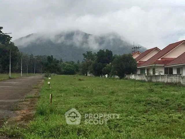 Scenic view of residential houses with lush greenery and misty mountains in the background.