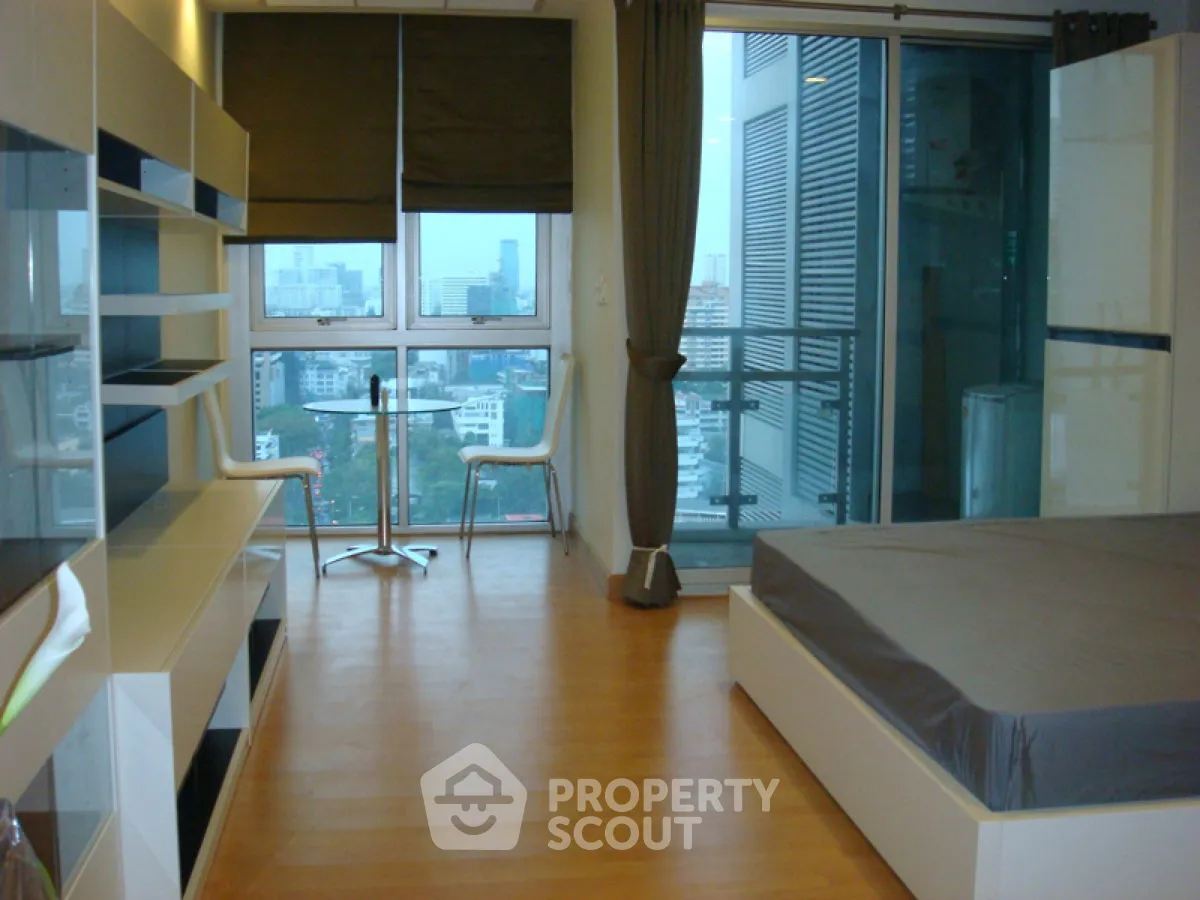 Modern bedroom with city view and balcony access in high-rise apartment