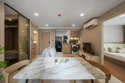 Modern open-plan living room with kitchen and dining area, featuring sleek furniture and appliances.