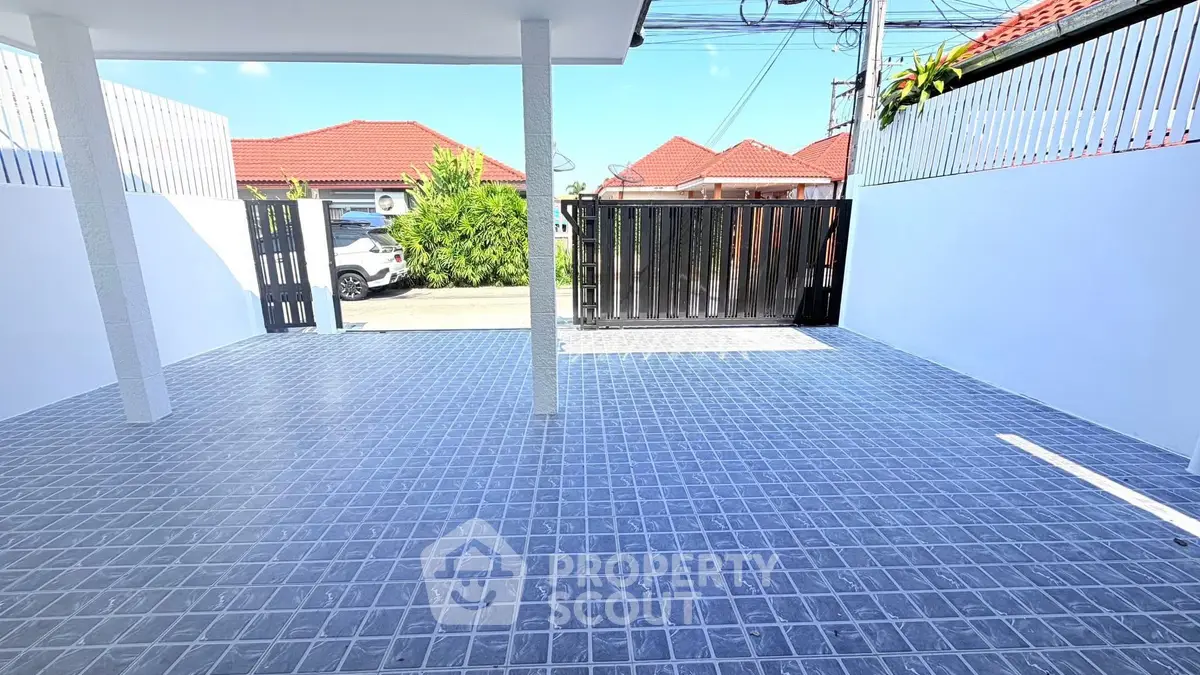 Spacious tiled driveway with modern gate and suburban view