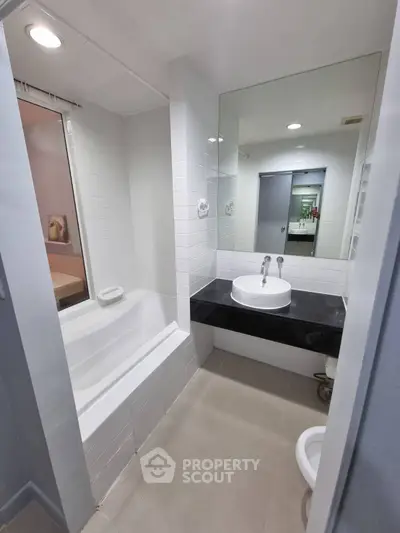 Modern bathroom with sleek white tiles and a stylish bathtub in a contemporary apartment.