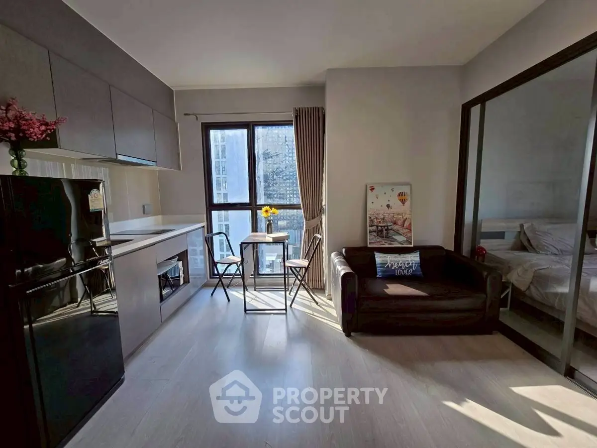 Modern apartment with open kitchen and cozy living area, featuring large windows and stylish decor.