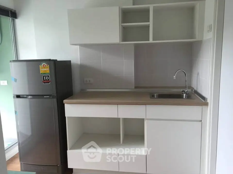 Modern kitchen with sleek cabinetry and stainless steel fridge in a compact layout.