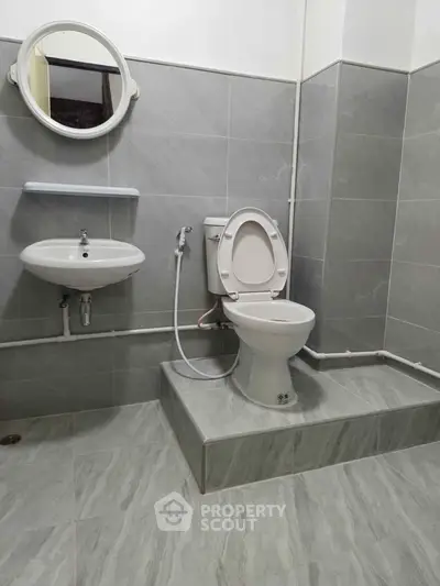 Modern bathroom with sleek grey tiles and round mirror