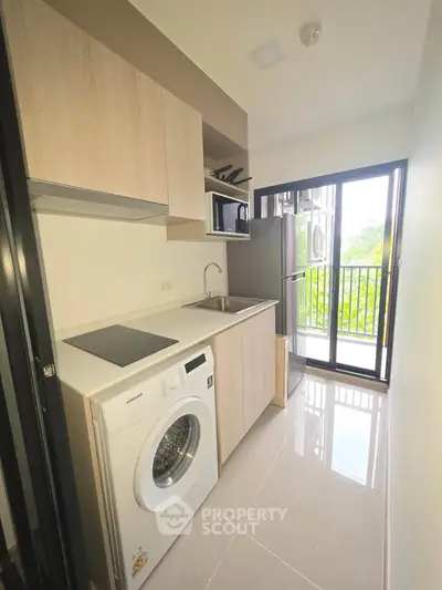 Modern kitchen with washing machine and balcony view in a bright apartment.