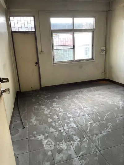 Unfurnished room with tiled floor and large window, ideal for renovation.