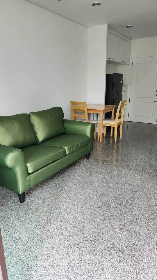 Spacious living room with green sofa and dining area in modern apartment