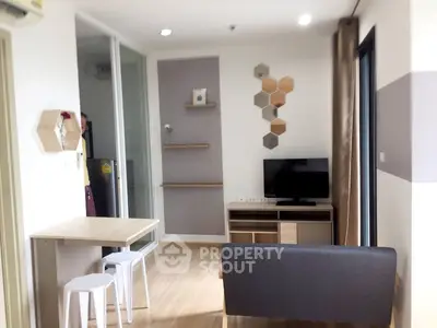 Modern living room with stylish decor and natural light, featuring a compact dining area and sleek furniture.