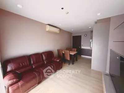 Spacious living room with leather sofa and dining area in modern apartment