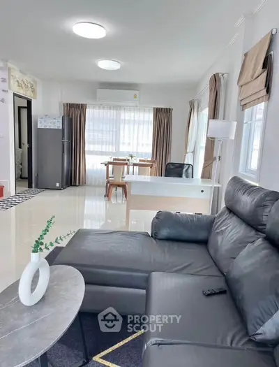 Spacious modern living room with sleek black leather sofa and elegant dining area