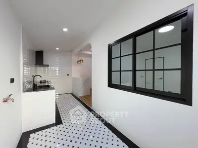 Modern kitchen with sleek black and white design, featuring gas stove and stylish lighting.