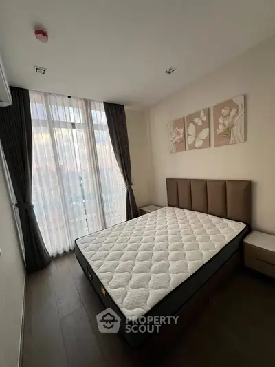 Modern bedroom with large window and stylish decor in a contemporary apartment.