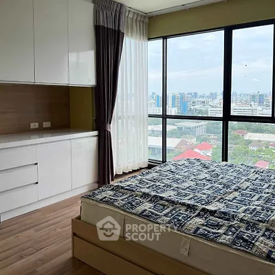 Spacious bedroom with city view and modern furnishings in high-rise apartment