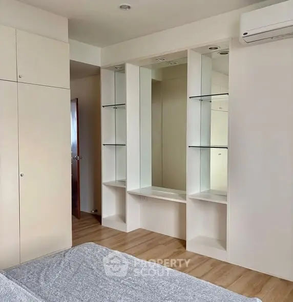 Modern bedroom with built-in storage and air conditioning, featuring sleek design and ample natural light.