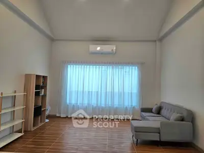 Spacious living room with modern sofa and large window, perfect for natural light lovers.