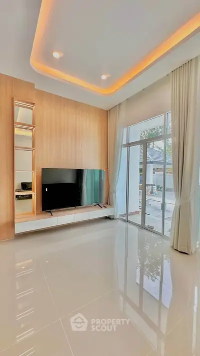 Modern living room with sleek TV setup and large windows offering natural light.