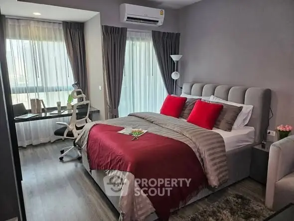 Modern bedroom with stylish decor and workspace, featuring large windows and elegant furnishings.