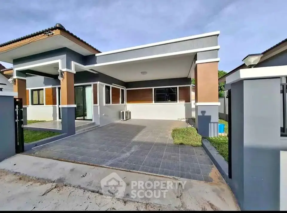 Modern single-story house with spacious driveway and contemporary design.
