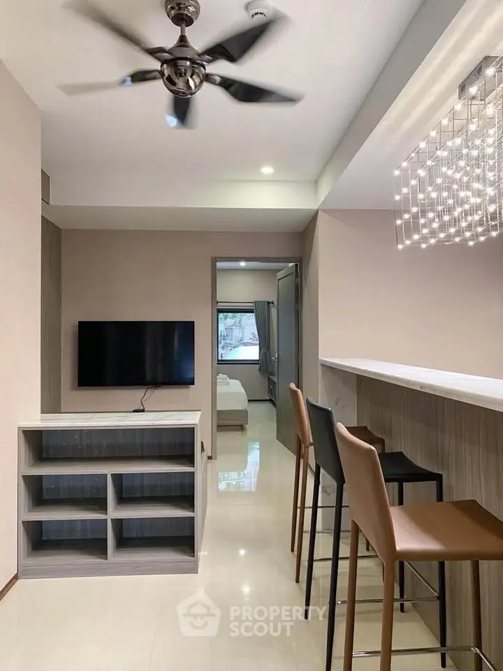Modern living room with sleek bar counter and stylish lighting, leading to a cozy bedroom.