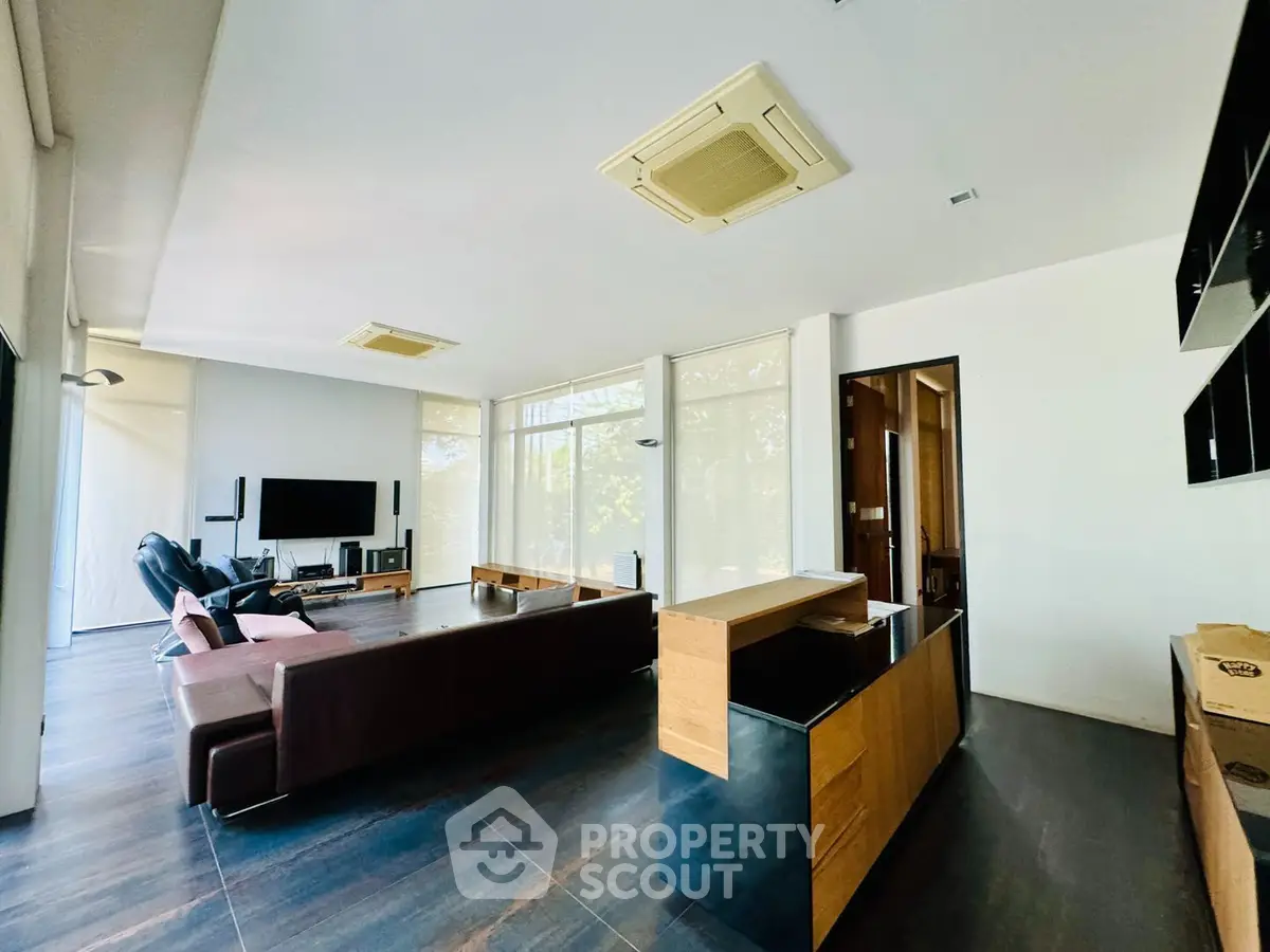 Spacious modern living room with sleek hardwood floors, large windows allowing ample natural light, and a contemporary open layout design, perfect for entertaining and relaxation.