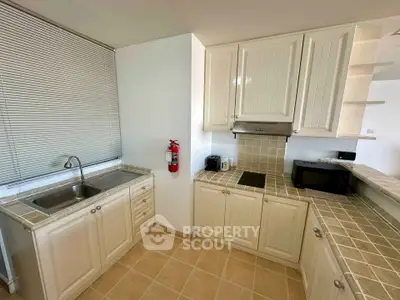 Charming kitchen with tiled countertops and modern appliances in a cozy apartment.