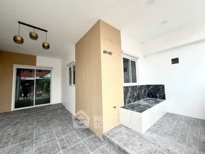 Modern minimalist home entrance with sleek tile flooring and stylish lighting fixtures.