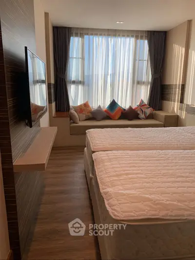 Cozy bedroom with twin beds and a sunlit window seat, perfect for relaxation.