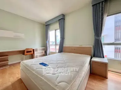 Spacious bedroom with large windows and modern furnishings in a high-rise apartment.