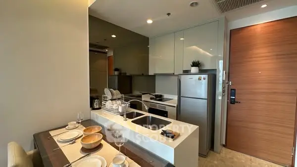 Modern kitchen with sleek cabinetry and dining setup in a compact apartment.