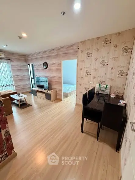 Spacious living room with modern decor and wooden flooring, leading to a cozy bedroom.