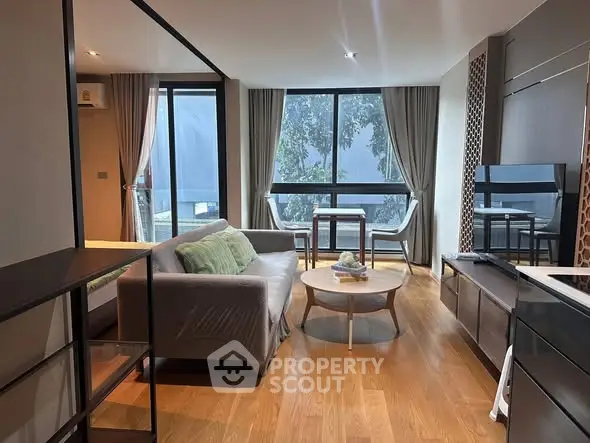 Modern living room with large windows, stylish furniture, and wooden flooring.