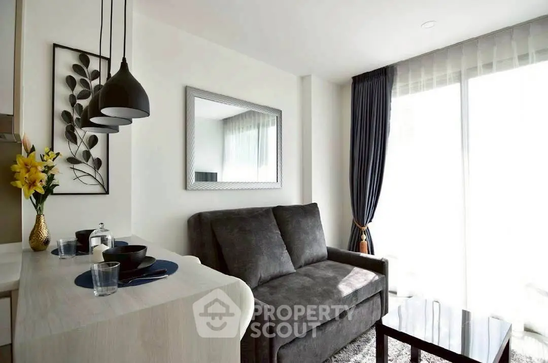 Modern living room with cozy sofa, stylish decor, and natural light from large windows.