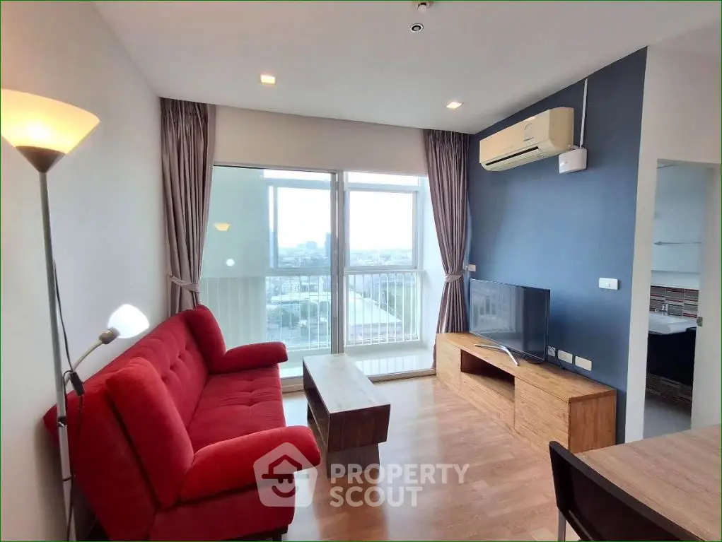 Modern living room with red sofa, wooden floor, and large window view.