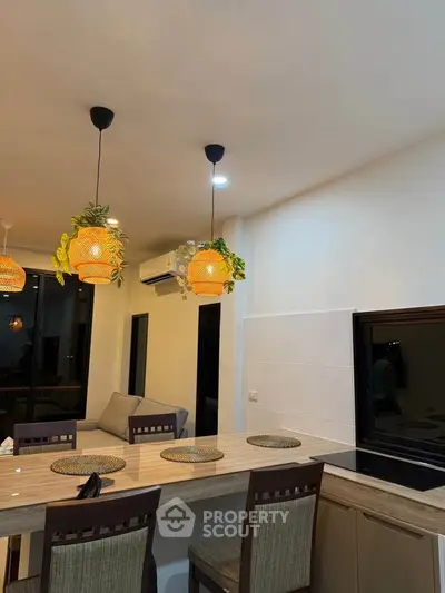 Modern kitchen with stylish lighting and dining area in open layout apartment.