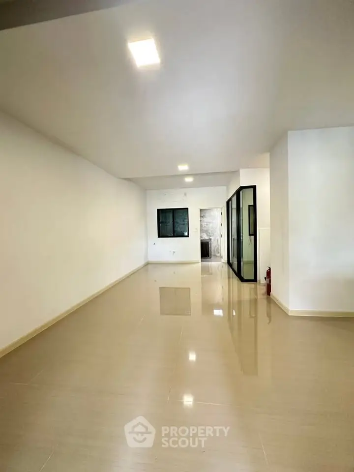 Spacious open-plan living area with glossy tiled floors and modern glass partition.