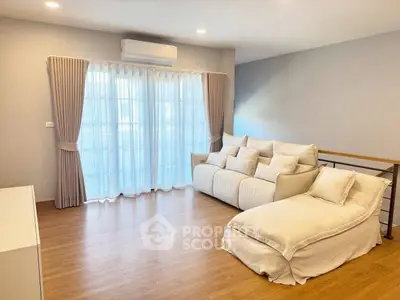 Spacious living room with elegant sofa and natural light through large windows.