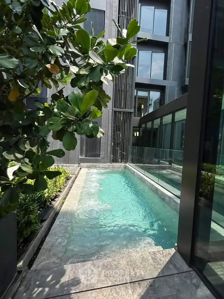 Luxurious modern building with sleek pool and lush greenery, perfect for urban living.