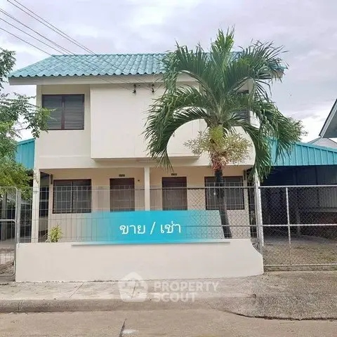 Charming two-story house with blue roof and palm tree in front, perfect for sale or rent.