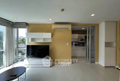 Modern living room with large windows and open kitchen layout in a stylish apartment.