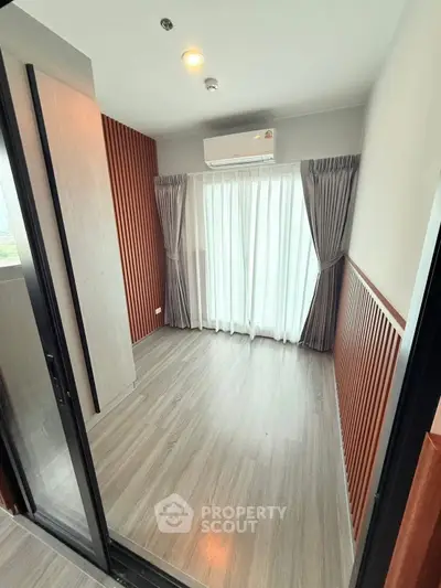 Modern small room with wooden accents and large window, perfect for cozy living or office space.