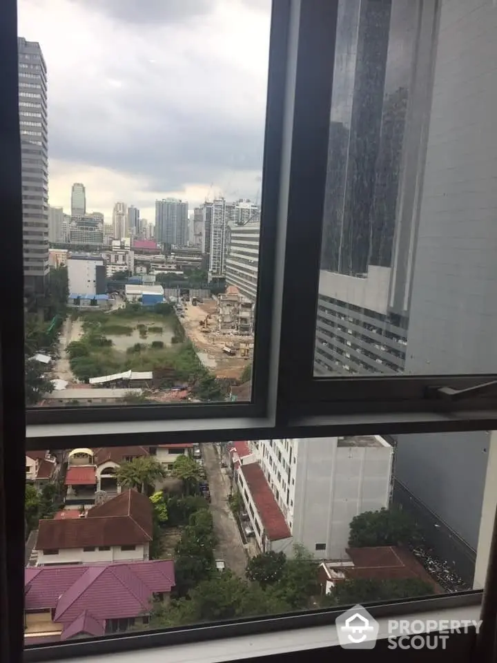 Captivating high-rise view from a modern urban apartment, showcasing a bustling cityscape with ongoing development, framed by a large window inviting natural light.