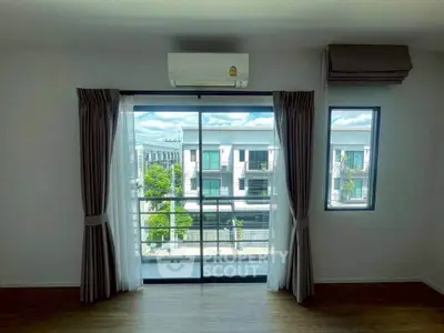 Bright living room with large windows and balcony view in modern apartment.