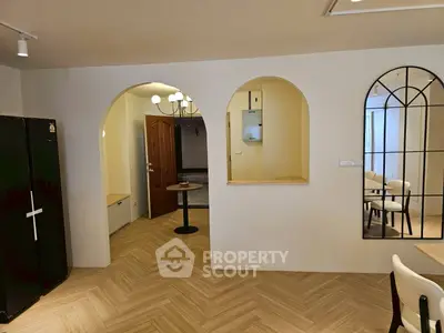 Charming interior with arched doorways and elegant mirror, featuring stylish herringbone flooring.
