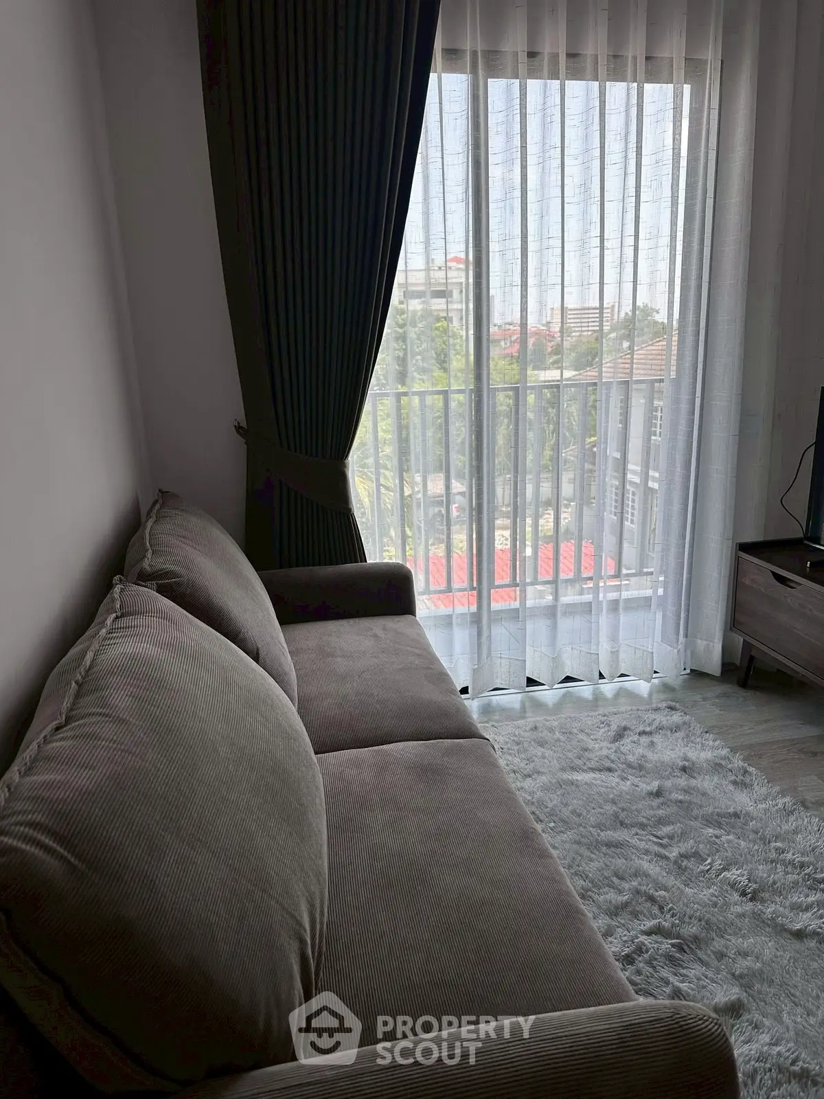 Cozy living room with plush sofa and city view through large window.