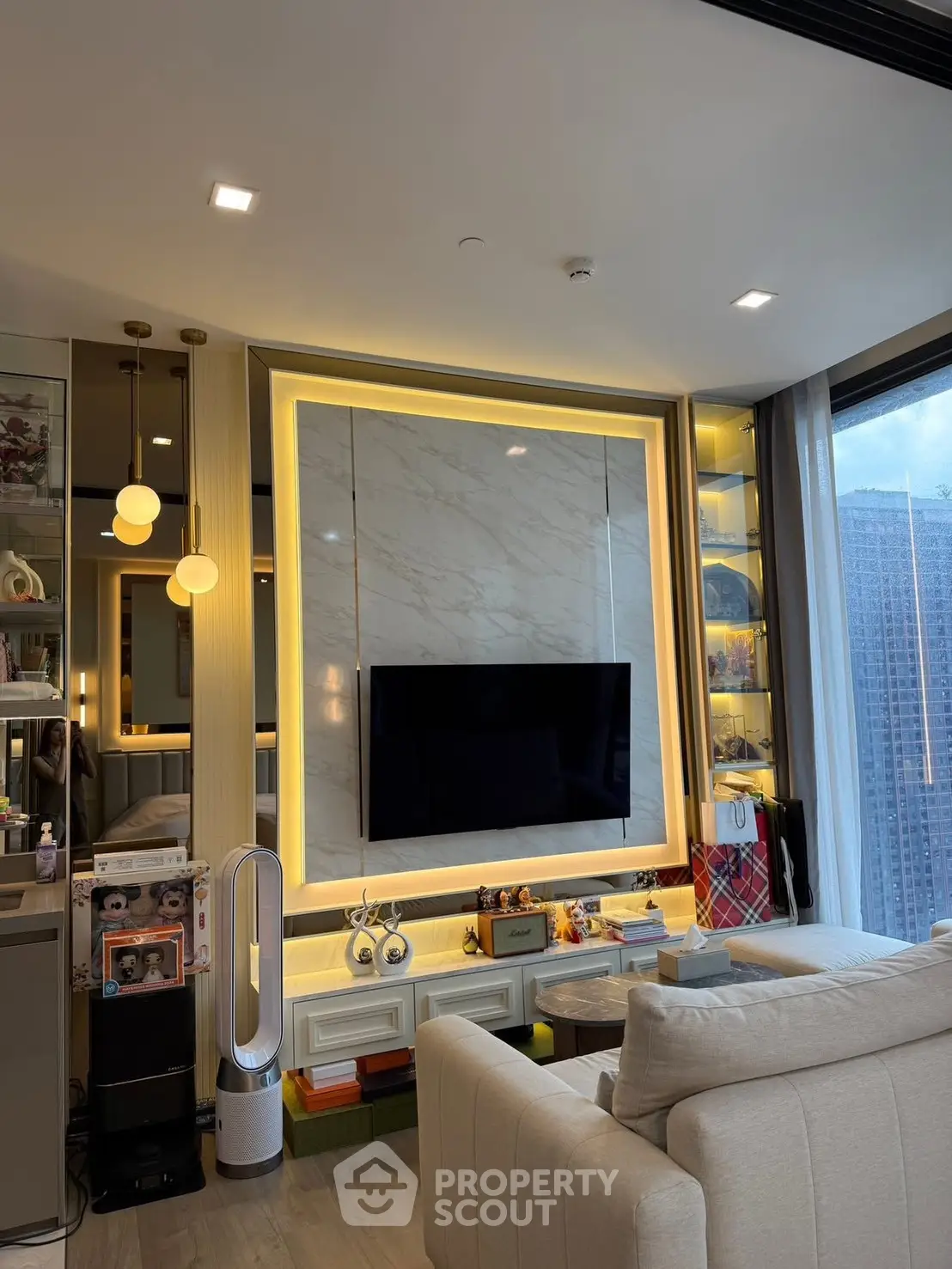 Modern living room with stylish decor and large TV, featuring elegant lighting and city view.